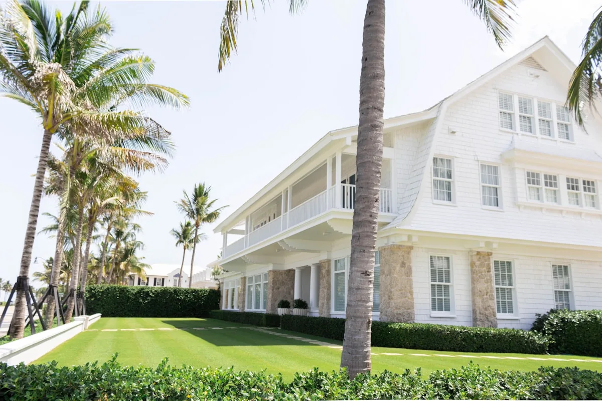 A white house with a lawn and palms
